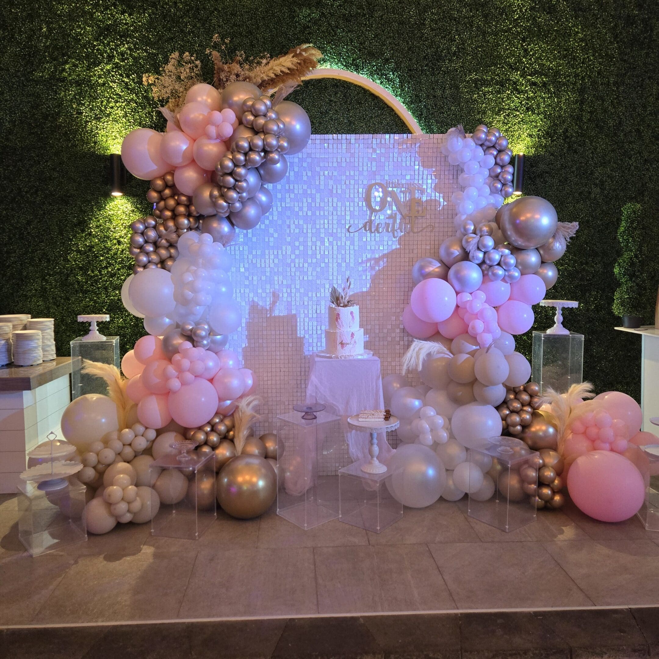Elegant pink and gold balloon arch decorations at an event.