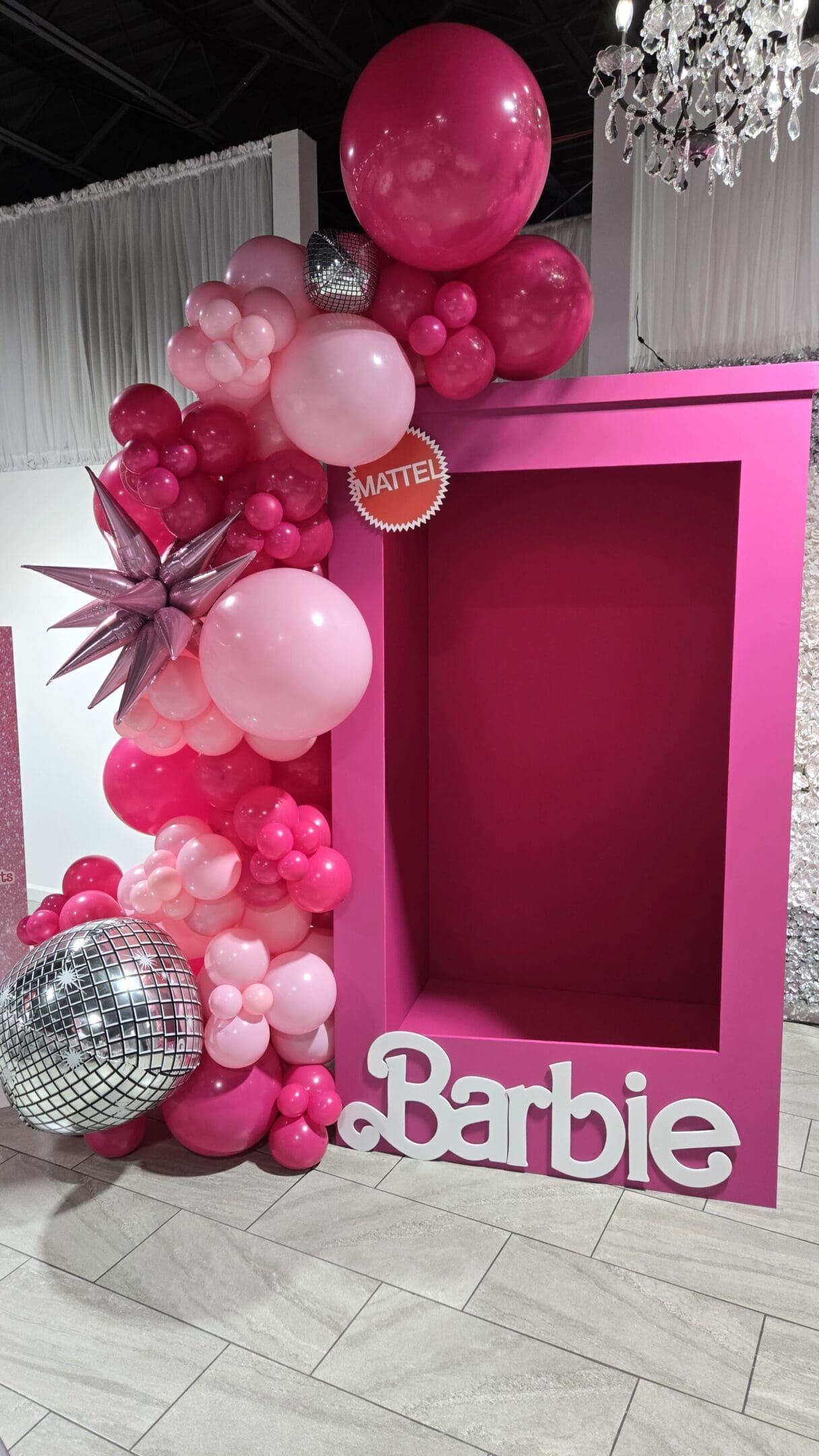 Pink Barbie-themed photo booth with balloons and disco ball.