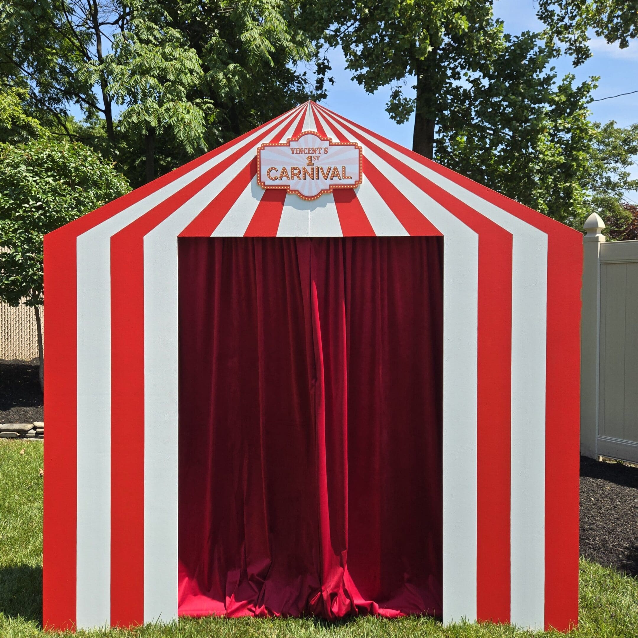 A red and white striped tent with a red velvet curtain entrance.