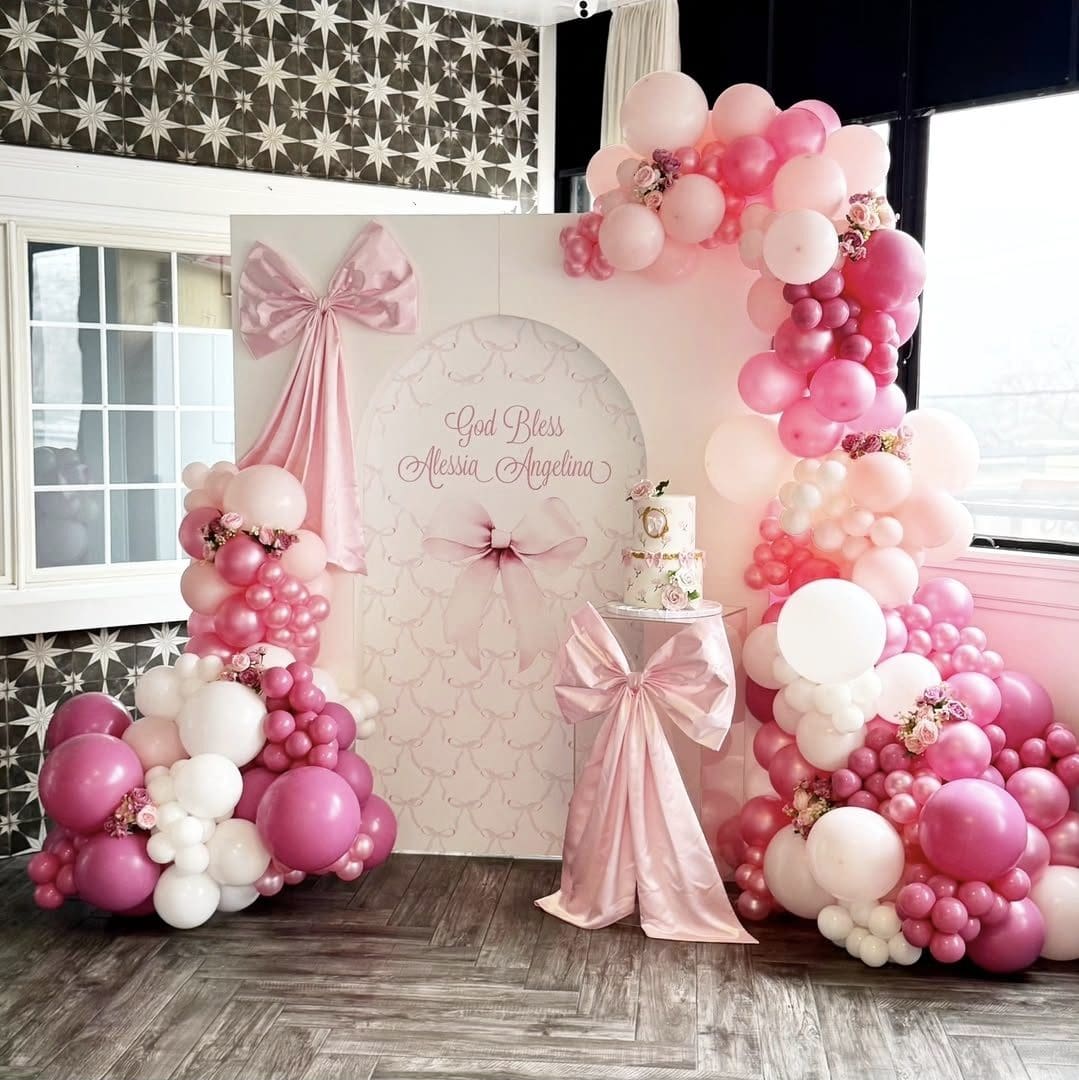 Elegant pink and white balloon decor with a large backdrop for a special event.